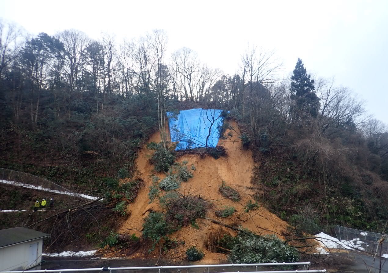 令和6年能登半島地震により埋立処分場管理通路法面に土砂崩れが発生したため、被害の拡大を防止するブルーシートを敷設